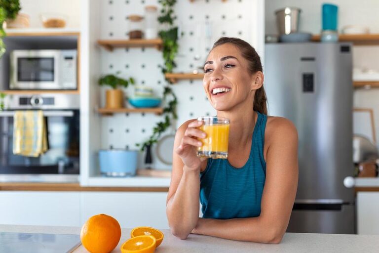 Enjoying fresh orange juice rich in vitamin C in a bright modern kitchen with citrus fruits on counter