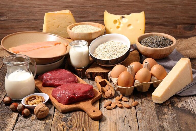 Fresh cheese, raw eggs, liver and red meat with nuts and grains arranged on rustic wooden table.