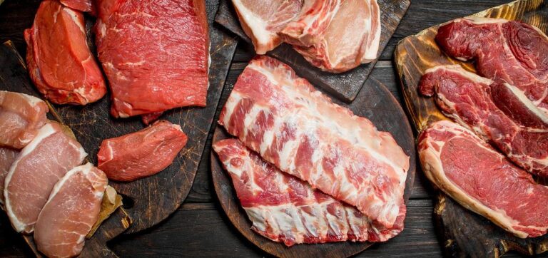 Vitamin B12 displayed as raw cuts of beef, lamb, and pork arranged on rustic wooden cutting boards, showcasing fresh meat varieties.